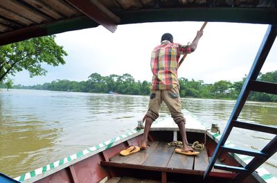Rear view of man standing on boat