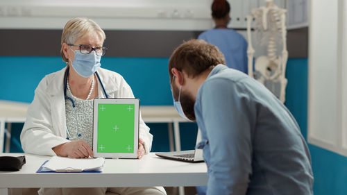 Doctor showing digital tablet screen to patient at clinic