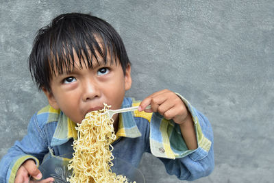 High angle view of boy eating noodles against wall