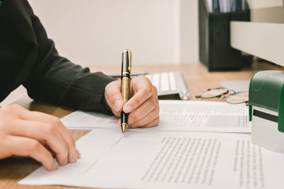 Midsection of businesswoman writing on document at office