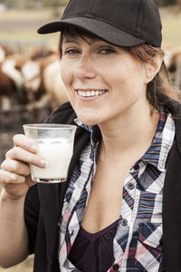 Portrait of smiling female farmer drinking milk in farm