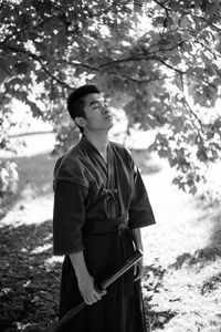 Young man standing against tree