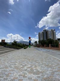 Rear view of man on street amidst buildings against sky