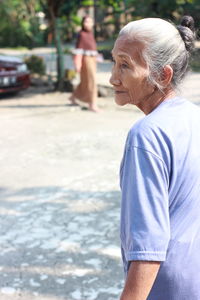 Midsection of woman looking away while standing outdoors