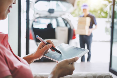 Midsection of woman signing on digital tablet while receiving delivery at home