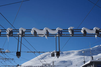 Low angle view of electricity pylon against clear blue sky