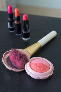 High angle view of blush with make-up brush and lipsticks on table