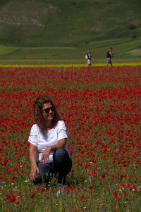 Young woman by red poppy flowers on field