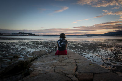 Rear view of woman standing by sea against sky