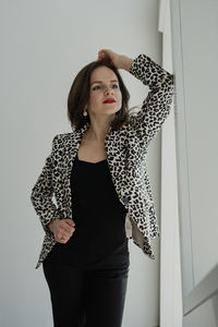 Portrait of young woman standing against wall