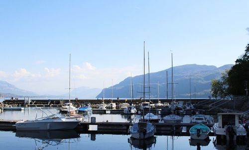 Boats moored at harbor against sky