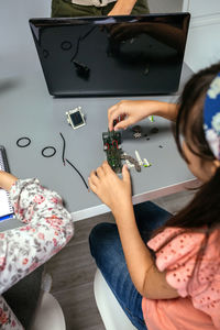 Female student screwing electrical circuits of machine in robotics class