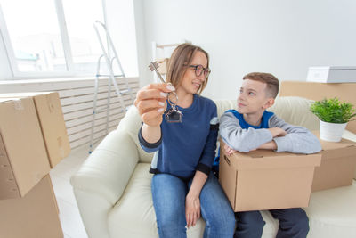 Young woman sitting in box at home