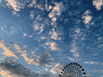 Low angle view of ferris wheel against cloudy sky