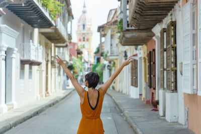 Full length of woman with arms outstretched standing in city