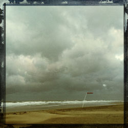 Scenic view of beach against cloudy sky