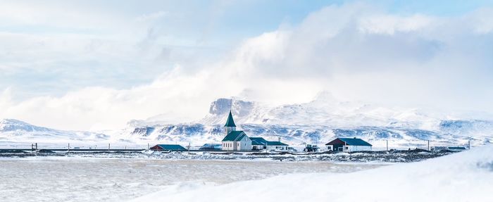 Scenic view of snowcapped mountains by sea against sky