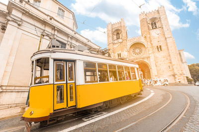 Yellow train on railroad track against buildings in city
