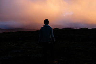 Rear view of a man on landscape at sunset