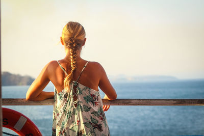 Rear view of woman looking at sea against sky