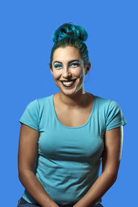 Portrait of smiling young woman against blue background