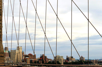 View of suspension bridge in city against sky