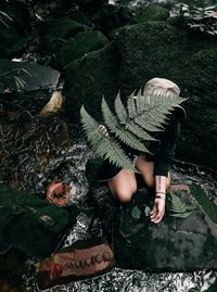 High angle view of woman by rock in forest