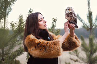 Portrait of young woman holding birds in winter