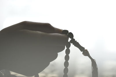 Close-up of hand holding cross against clear sky