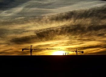 Low angle view of silhouette electricity pylon against sky during sunset