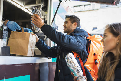 Customers purchasing food from owner at food truck