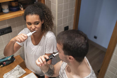 Couple brushing teeth together while standing in bathroom at home
