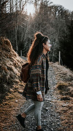 Full length of young woman standing in forest