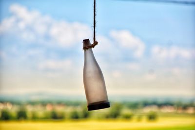 Low angle view of bottle hanging on metal structure against sky