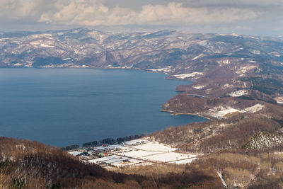 Aerial view of townscape by sea against sky