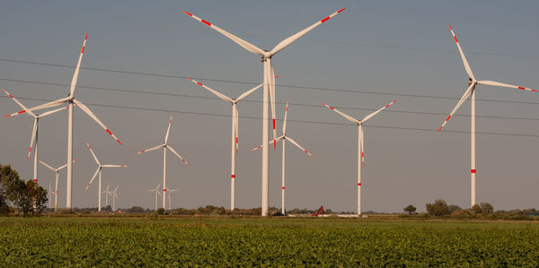 Wind turbines on field against sky