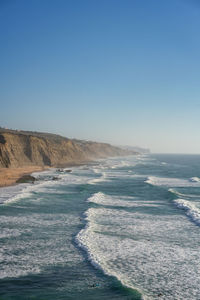 Magoito beach with surfers surfing on the sea waves in sintra, portugal