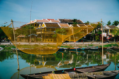 Houses by lake and buildings against sky