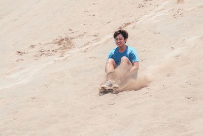 Portrait of young man on sand at beach