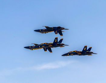 Low angle view of airplane flying against clear blue sky