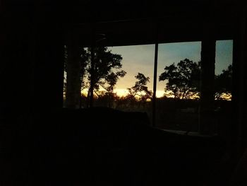 Silhouette trees against clear sky seen through window