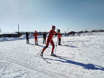 People skiing on snowy field against sky