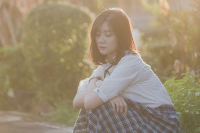 Young woman with eyes closed sitting at park