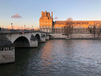 Arch bridge over river against sky in city