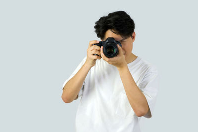 Portrait of man photographing against white background