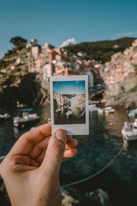 Midsection of person holding camera against sky