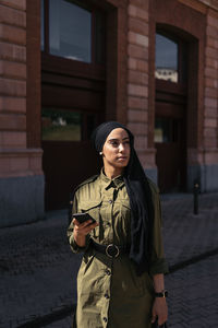 Young woman standing against building