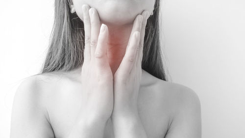 Close-up of woman with neck pain over white background