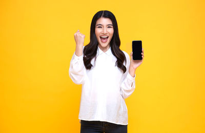 Portrait of a smiling young woman against yellow background