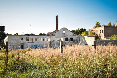 Abandoned building in field against clear sky